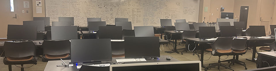 Library Classroom, also called the e-classroom. This room has rows of tables with computers facing a whiteboard.