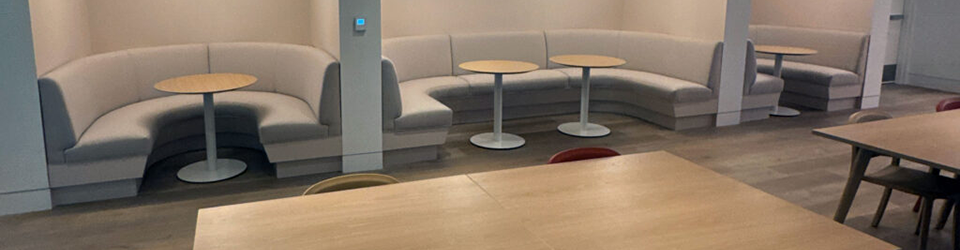 Main area of the study commons. Multiple rounded booth seating with modern lighting and round tables.